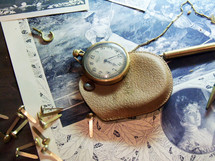 An old pocket watch adorns a museum case with old drawings of a women from the late 1800s to early 1900s telling the story of a time long ago when life was simple and history was being made at the turn of the century. 