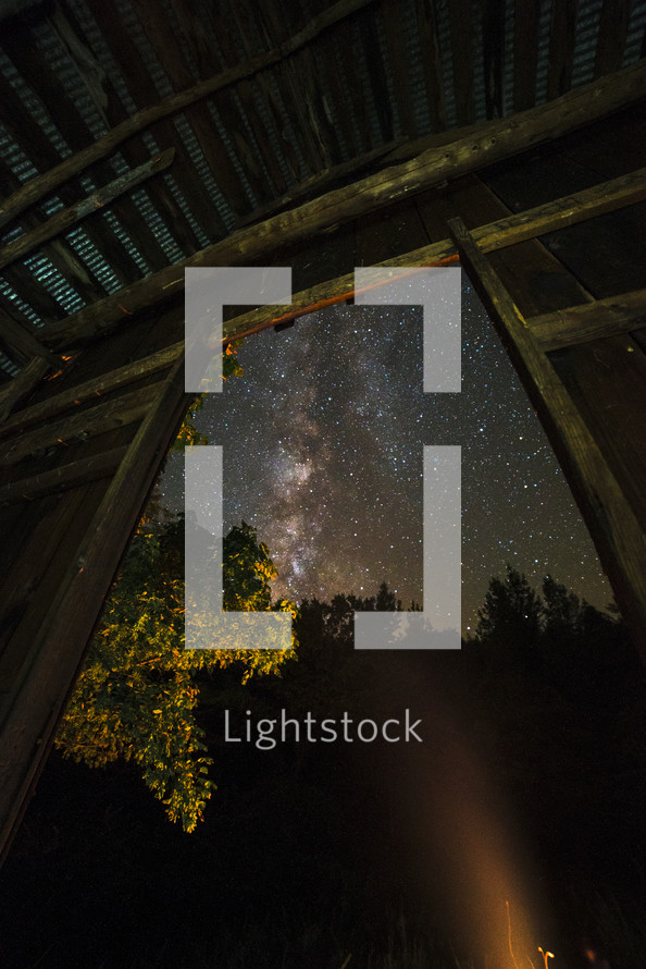 view of stars in a night sky through a barn door 