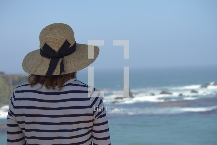 woman in a hat watching the ocean 