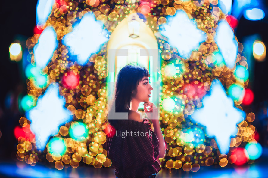 a woman standing in front of a Christmas tree