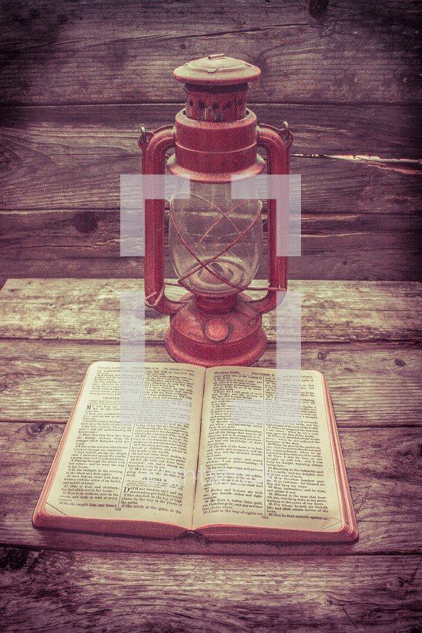 lantern and open Bible on wood boards 