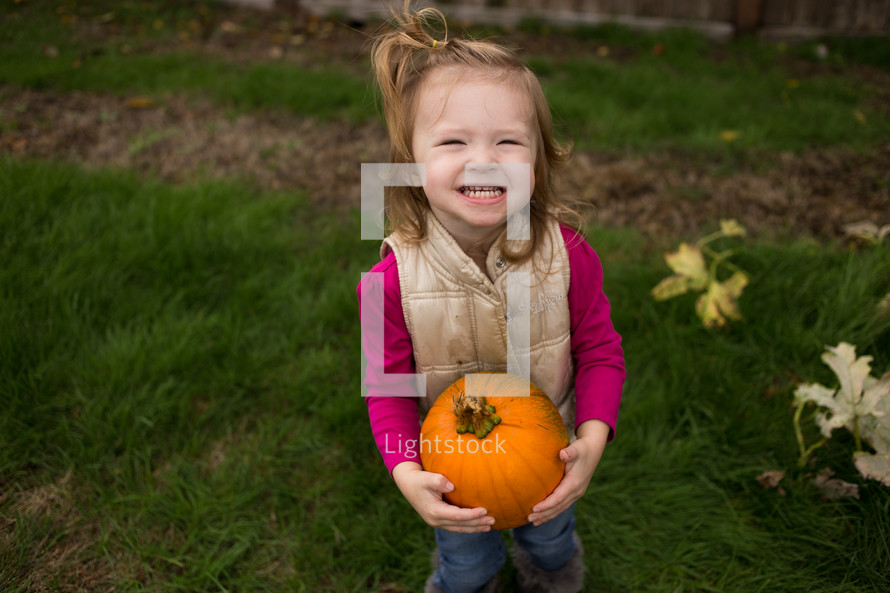 a girl child with a pumpkin 