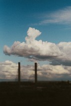 Silhouette of smoke stacks covered by clouds.
