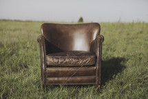 a leather chair alone in a field 