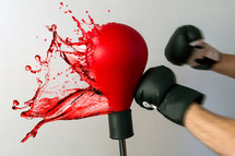Angry man punching with boxing gloves. Red liquid splash
