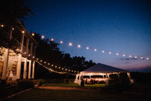 strings of lights and a tent at a wedding reception at night 