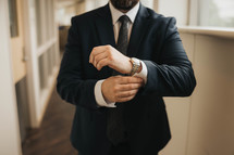 a man in a suit adjusting his watch