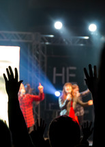 A worship team sings as people lift their hands