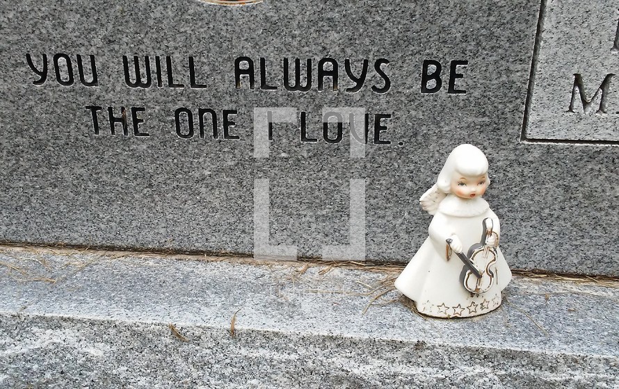 A little ceramic Angel figure with a small violin sits on a tombstone with the words "You will always be the one I love".  White Cherub female Angel figure sitting on a grave headstone.