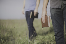 men standing in a field of tall grass holding Bibles 
