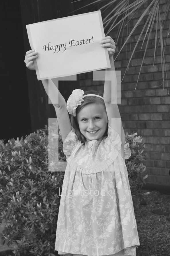 A little girl holding a Happy Easter sign in black and white 