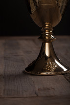 A golden communion goblet on a rustic wooden table.