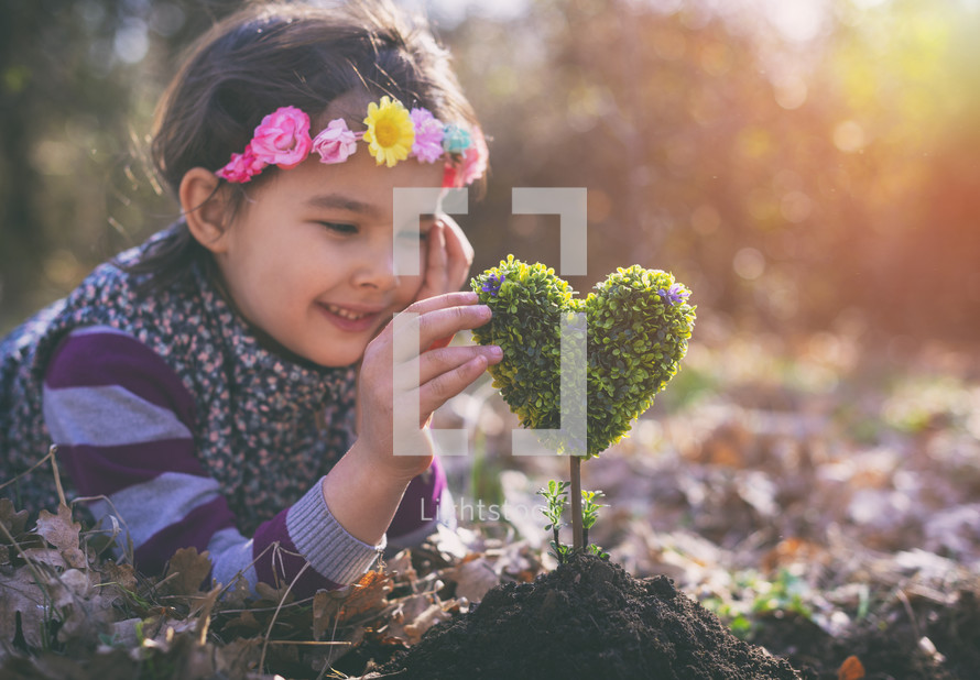 girl planting a heart-shaped tree and dreaming of a beautiful future