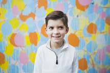 boy child standing in front of a colorful wall 