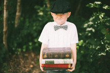 boy child straining holding a stack of books 