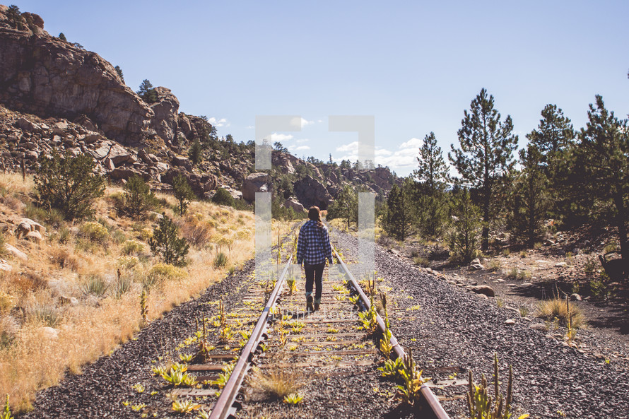 a woman walking down abandoned train tracks 