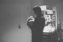 a father holding a newborn baby in a NICU