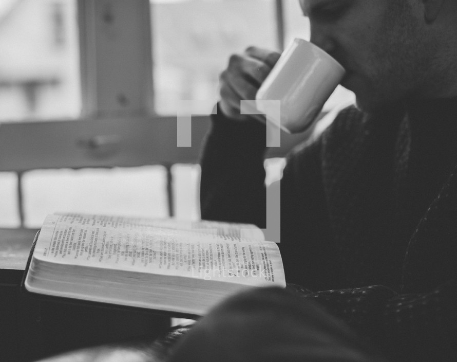 A man drinking coffee and reading a Bible 