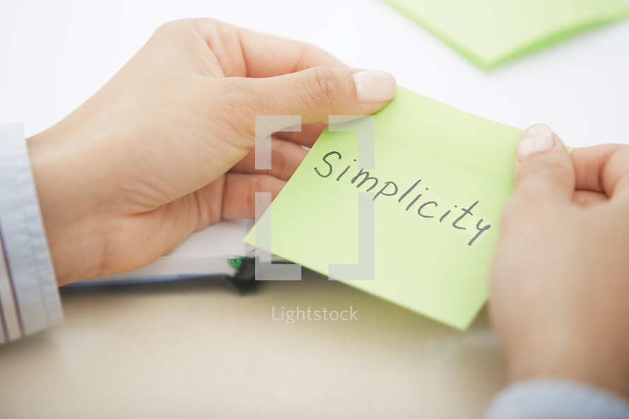 a woman holding a sticky note with the words simplicity 