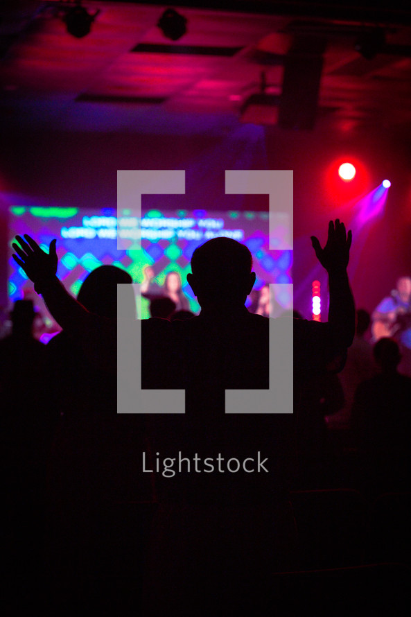 silhouette of raised hands during a contemporary worship service 