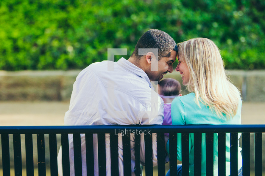 couple sitting on a bench forehead to forehead 