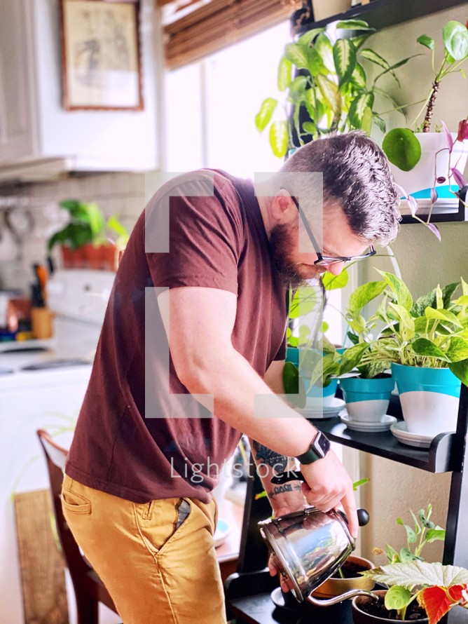 a man watering houseplants 
