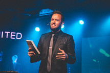 a pastor holding a Bible during a worship service 