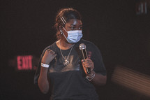a woman on stage wearing a face mask 
