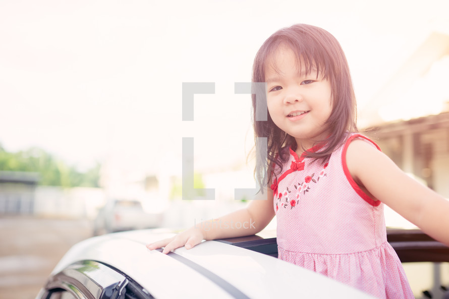 Little girl in the car looking out a sunroof.