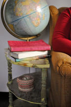 globe and books on an end table next to an armchair 