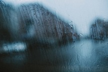a street seen through a window with rain falling heavily