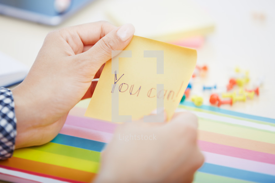 a woman reaching for a sticky note with the words you can 