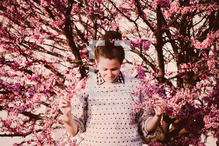 a young woman touching pink blossoms 