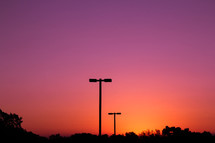 silhouettes of street lamps against a pink sky