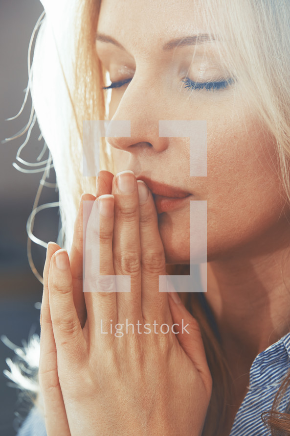Blond woman with closed eyes praying