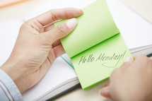 a woman reaching for a sticky note with the words hello Monday 