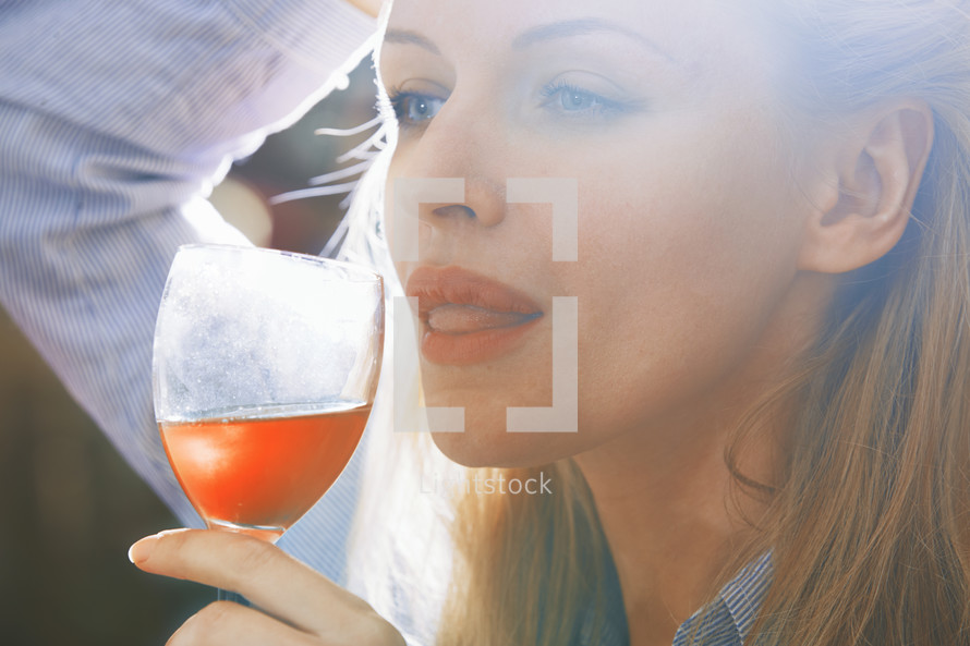 Carefree blond woman tasting and drinking wine at the party