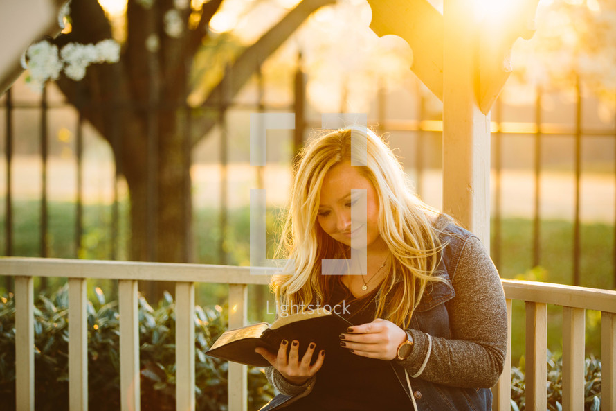 a woman reading a Bible in a gazebo 