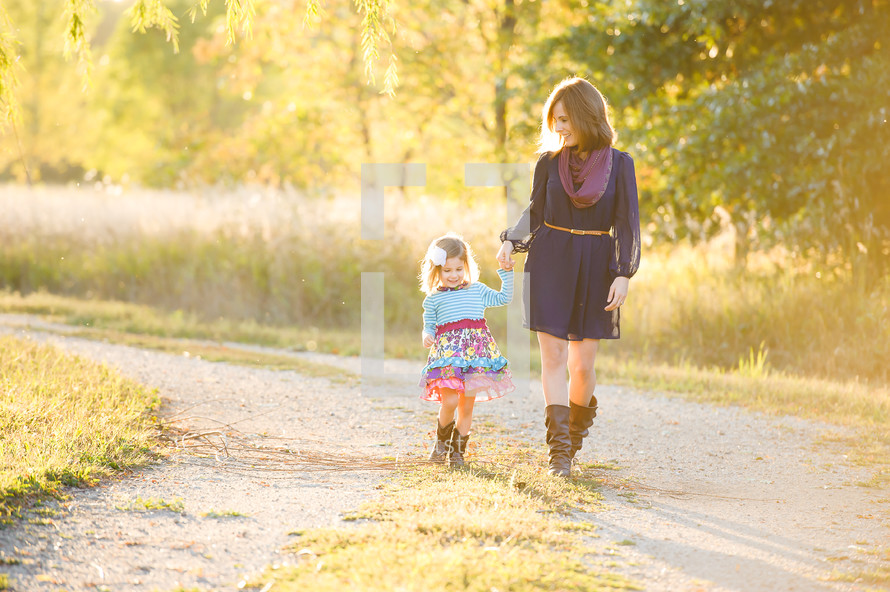 A mother and daughter walking holding hands outdoors 