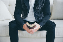 a man sitting on a couch holding a Bible 