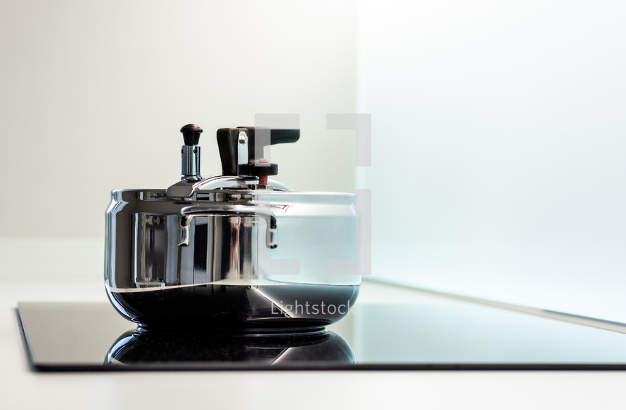 Stainless steel pressure cooker on a modern induction stove top