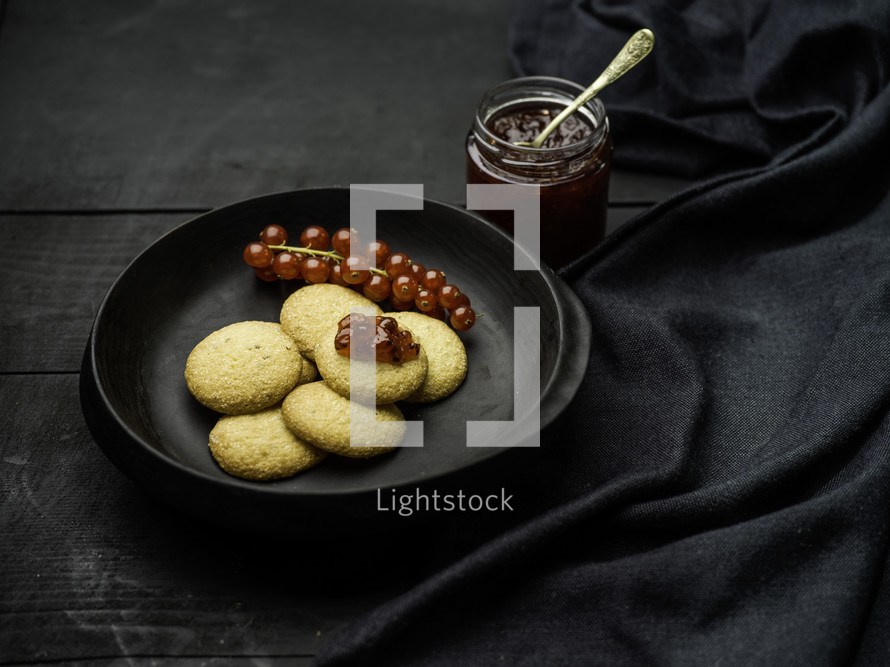 Cookies with jelly and berries on black table