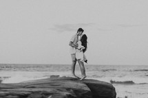 a couple kissing on a rocky shore 