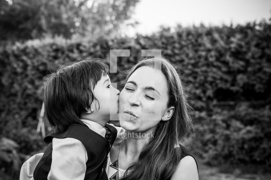 A little boy kissing a woman on the cheek 