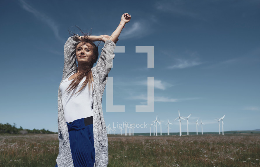 a woman standing in front of a wind farm 