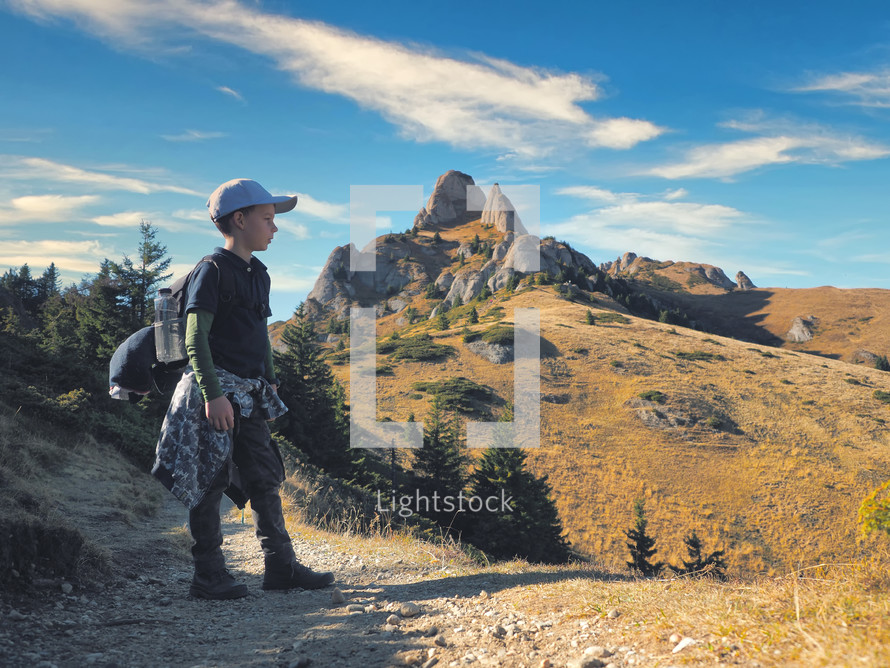 boy with backpack hiking in scenic mountains