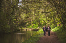 a couple walking on a trail by a river 