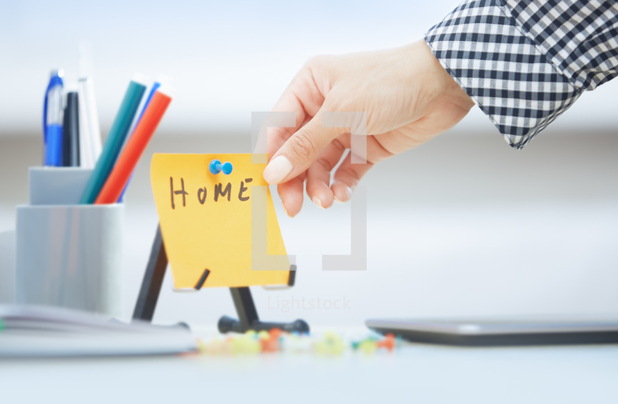 woman holding a sticky note with the word home 