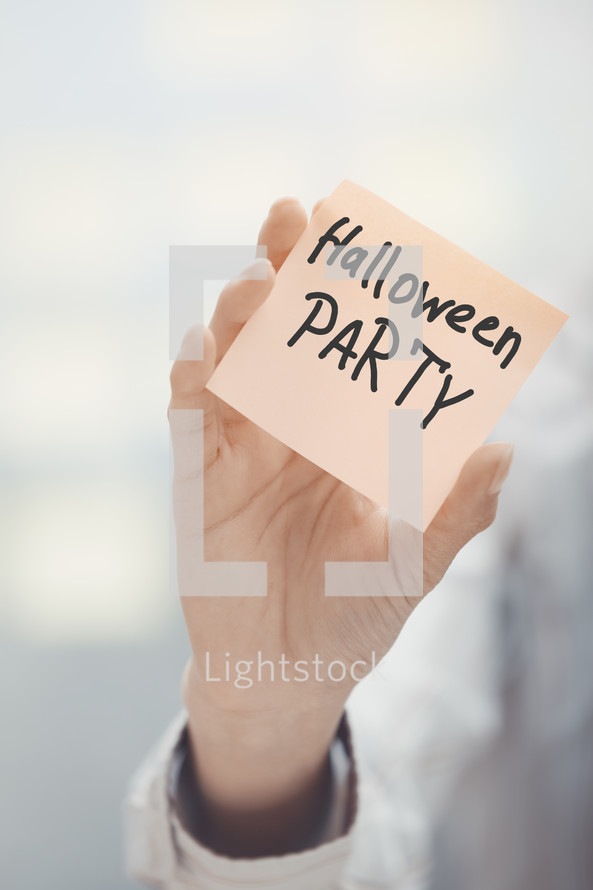 a woman holding a sticky note with the words Halloween Party