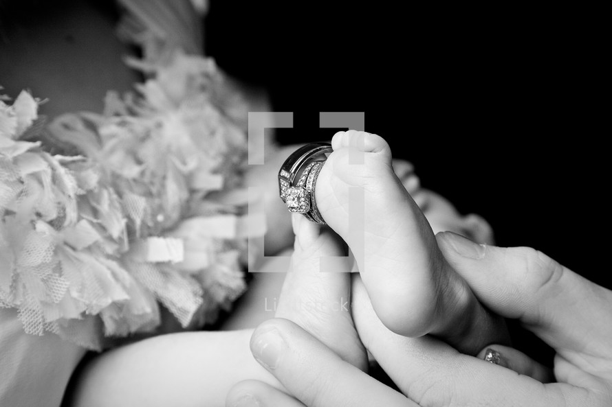 wedding band and engagement ring on the toes of a newborn infant